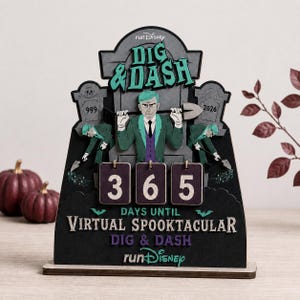 May include: A runDisney Dig & Dash countdown calendar featuring a central figure in a green suit holding a shovel, flanked by two tombstones marked 999 and 2026. Three rotating blocks display the number 365 above the text Days Until Virtual Spooktacular.
