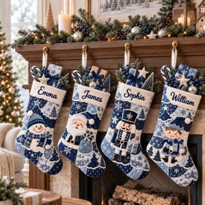 Op de afbeelding: Vier blauw-witte kerstsokken hangen aan een schoorsteenmantel, elk met een unieke geborduurde naam: Emma, James, Sophia en William. De sokken zijn versierd met feestelijke figuren, waaronder een sneeuwpop, de Kerstman, een notenkraker en een elf.