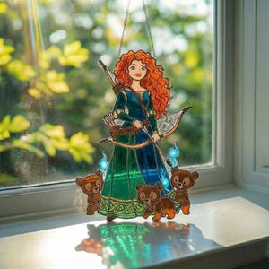 K&ouml;nnte beinhalten: Ein Buntglas-Suncatcher mit einer Figur mit langem, lockigem rotem Haar in einem dunkelgr&uuml;nen Kleid. Die Figur tr&auml;gt einen Bogen und einen K&ouml;cher mit Pfeilen, begleitet von drei kleinen braunen B&auml;renjungen und leuchtend blauen Irrlichtern.