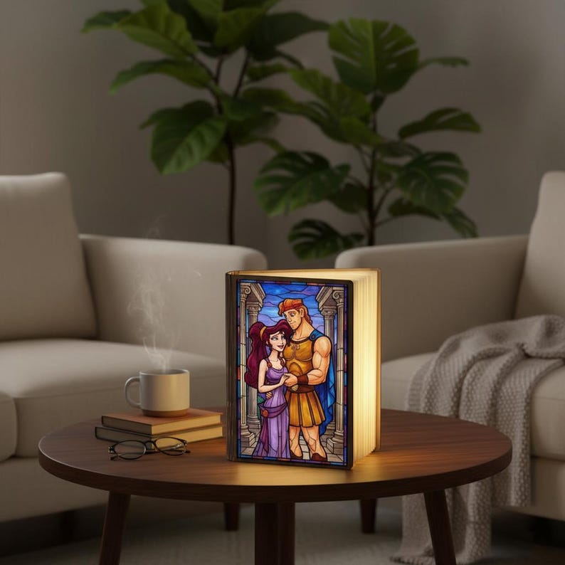May include: A decorative book-shaped lamp with a stained-glass design featuring a cartoon couple. The lamp is illuminated, casting a warm glow. The image on the lamp depicts a man and woman in a colorful, classical style. The lamp is on a wooden table.
