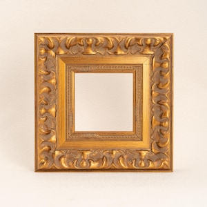 May include: A square picture frame with a metallic gold finish. The frame features a wide, ornate border with repeating sculpted patterns and a narrower inner border decorated with a series of small, raised circular beads in a linear arrangement.