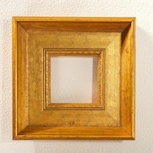 以下が含まれることがあります： 詳細な多層デザインの正方形の金色のフォトフレーム。フレームは、より小さな内側のフレームを備えた、質感のあるアンティークの外観をしています。フレームは空で、写真やアートワークの準備ができています。