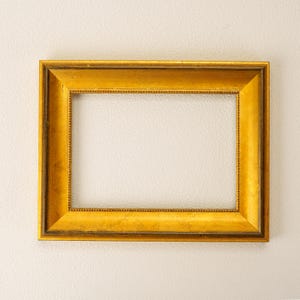 Op de afbeelding: Een rechthoekige, goudkleurige fotolijst met een sierlijk ontwerp. De lijst heeft een getextureerd oppervlak en is leeg, klaar voor een foto of kunstwerk. De lijst is een klassieke stijl, geschikt voor diverse interieurstijlen.