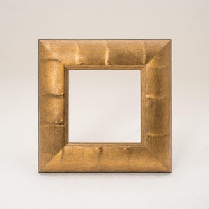 May include: Square, gold-colored picture frame with a textured surface. The frame has a simple, classic design and is suitable for displaying photos or artwork. The frame is approximately 6 inches by 6 inches.