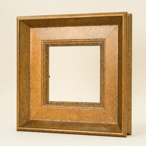 May include: A square, ornate picture frame with a gold finish. The frame has a layered design with a detailed inner border. The overall style is vintage and decorative, suitable for displaying photographs or artwork.