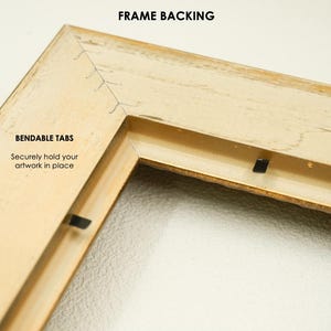 May include: Close-up of a corner of a beige picture frame. The frame has a distressed finish and features the text "FRAME BACKING" and "BENDABLE TABS" with the phrase "Securely hold your artwork in place".