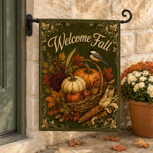 Pode incluir: Uma bandeira de jardim retangular com fundo verde escuro e o texto Welcome Fall em letras douradas. O design apresenta uma cesta de vime cheia de abóboras laranja, bagas vermelhas, folhas de outono, trigo e milho, com um pequeno pássaro pousado na alça.