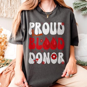 Proud Blood Donor T-Shirt, National Blood Donor Month Tee, Red Ribbon & Blood Drop Design, Awareness Apparel for Volunteers