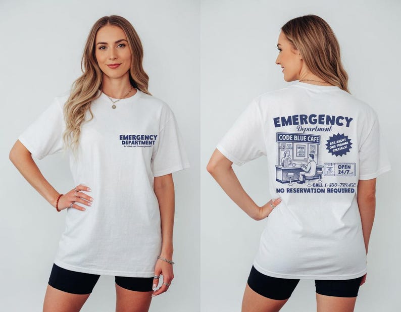 May include: White t-shirt with "Emergency Department" printed on the front and back. The back of the shirt features a graphic for "Code Blue Cafe" with additional text and illustrations. The shirt is worn with black shorts.