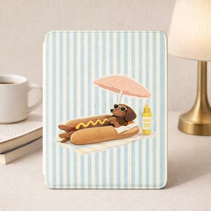 Könnte beinhalten: Eine Tablet-Hülle mit einer Illustration eines Dackels, der sich auf einem Hotdog entspannt, eine Sonnenbrille trägt und unter einem rosa Sonnenschirm liegt. Eine Flasche Sonnencreme SPF 50 ist ebenfalls vorhanden. Der Hintergrund hat blaue und weiße Streifen.