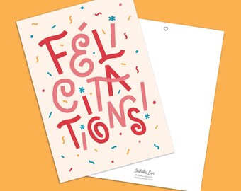 May include: A greeting card with the word "FÉLICITATIONS!" in red and pink lettering, with confetti and star accents. A blank white card is next to it. The background is orange.