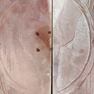 May include: Close-up of a light brown wooden surface with a circular design and four small dark brown dots in the center.