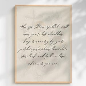 May include: A framed print with a light beige background and floral accents. The text in elegant script reads: "Always throw spilled salt over your left shoulder, keep rosemary by your garden gate, plant lavender for luck, and fall in love whenever you can."