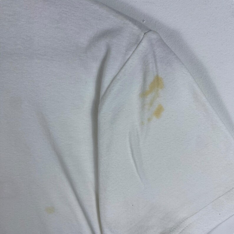 May include: White t-shirt with a yellow stain on the sleeve.