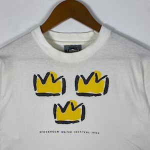 May include: White t-shirt with three yellow crowns and the text "STOCKHOLM WATER FESTIVAL 1994" printed on the front.