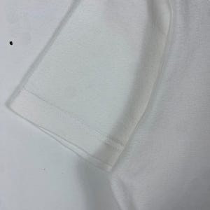 May include: Close-up of the white fabric of a t-shirt, showing the stitching along the edge of the sleeve.