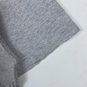 Może przedstawiać: Zbliżenie na tkaninę szarej koszulki z melanżu. Tkanina jest miękka i fakturowana.