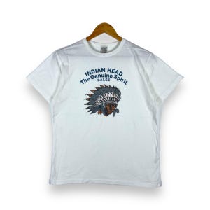 May include: White t-shirt featuring a graphic of an Indian head wearing a headdress. The text "INDIAN HEAD The Genuine Spirit CALEE" is printed on the shirt.