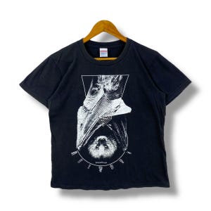 May include: Black t-shirt with a white graphic print of a bat hanging upside down with a geometric design. The text "Transcendental" is printed below the bat.