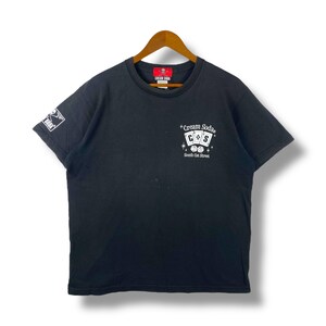 May include: Black short-sleeved t-shirt with a white graphic of playing cards and the text "Cream Soda South Cat Street".