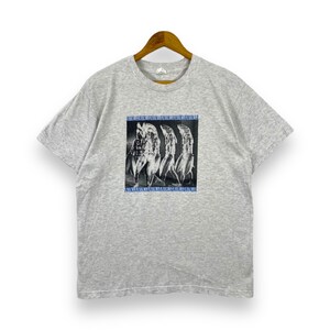 May include: A gray short-sleeved t-shirt with a graphic print of three stylized figures. The figures are black and white and have a blue outline. The text "NINJANINJANINJANINJANINJANINJA" is printed in blue above and below the figures.