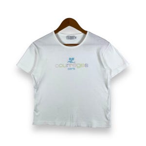 May include: White short-sleeved t-shirt with a colorful "Courr&egrave;ges Paris" logo embroidered on the front.