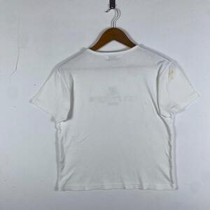 May include: White short-sleeved t-shirt with a faded graphic print on the front. The print says "Backstreet Boys" in a light blue color.