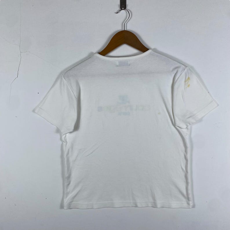 May include: White short-sleeved t-shirt with a faded graphic print on the front. The print says "Backstreet Boys" in a light blue color.