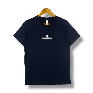 Puede incluir: Camiseta azul marino con cuello redondo y el texto "Caffè Macs" en blanco, junto con un logotipo de manzana blanca. La camiseta está colgada de una percha de madera.