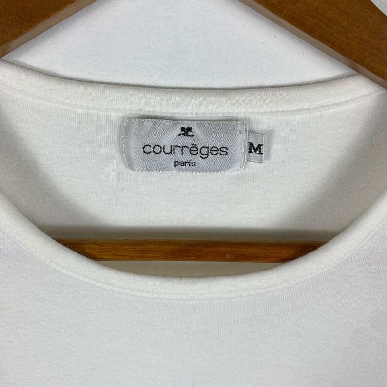 May include: White t-shirt with a black label that reads "Courr&egrave;ges Paris" and a size "M" tag.