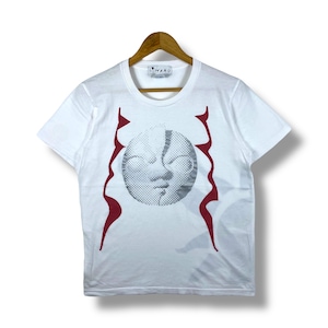 May include: White t-shirt with a graphic design featuring a face and red wavy lines. The shirt is hanging on a wooden hanger. The brand name "TARO" is printed on the collar.