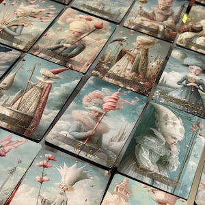 May include: A collection of fantasy art tarot cards. Each card features a unique illustration with soft colors, depicting whimsical figures in ornate costumes and surreal landscapes. The cards are arranged in a grid, showcasing the variety of designs.