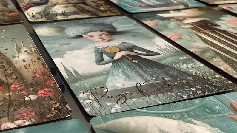 May include: Tarot card featuring a woman in a blue dress with a gold pendant, standing in a field. The card is labeled "Page of Pentacles" in gold script. Other cards with similar artwork are visible.