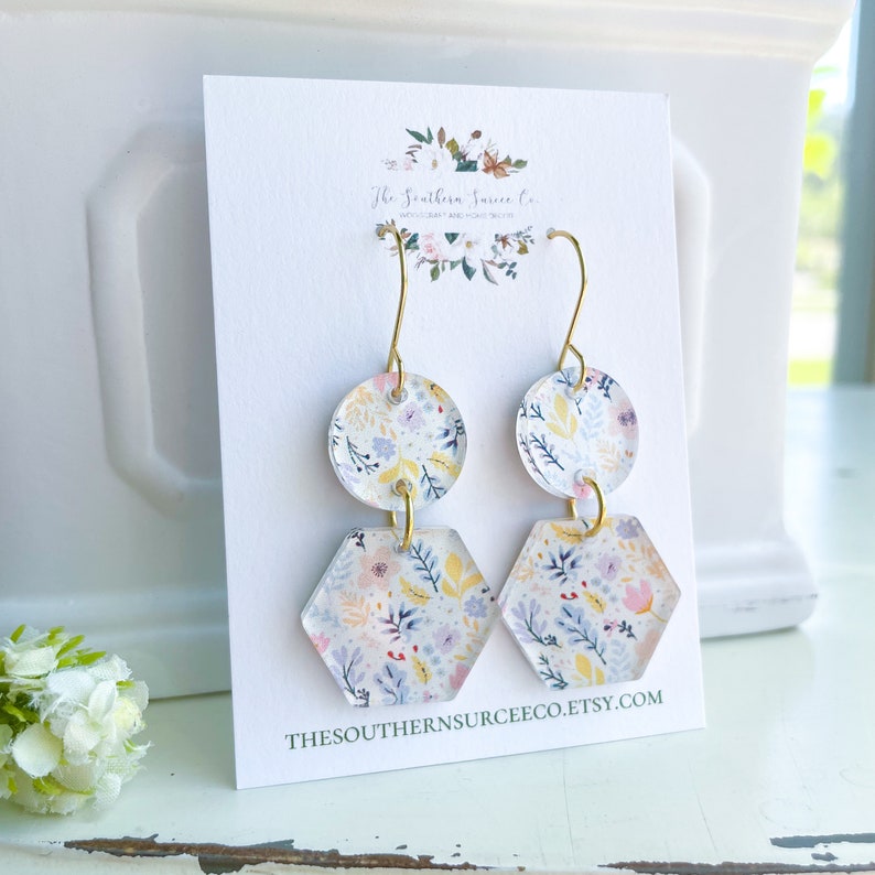 May include: Floral print earrings with gold-colored hooks. Each earring features a round top and a hexagon-shaped bottom. The earrings are on a white card with the text "The Southern Surcee Co." and "THESOUTHERNSURCEECO.ETSY.COM".
