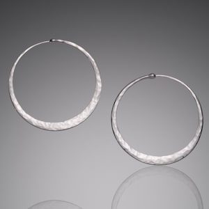 May include: A pair of silver hoop earrings with a hammered texture.