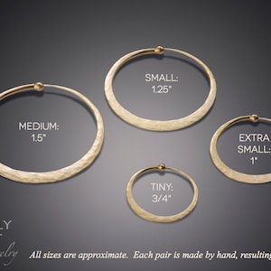Size comparison of hammered solid 14k gold hoop earrings against dark gray background with Mostly Sweet Jewelry logo. Four different sizes clearly labeled: Medium (1.5"), Small (1.25"), Extra Small (1"), and Tiny (3/4"). Each hoop displays the same hammered texture and endless closure design. Text at bottom notes "All sizes are approximate. Each pair is made by hand, resulting in variation." Warm gold tone shows luxury alternative to silver version.