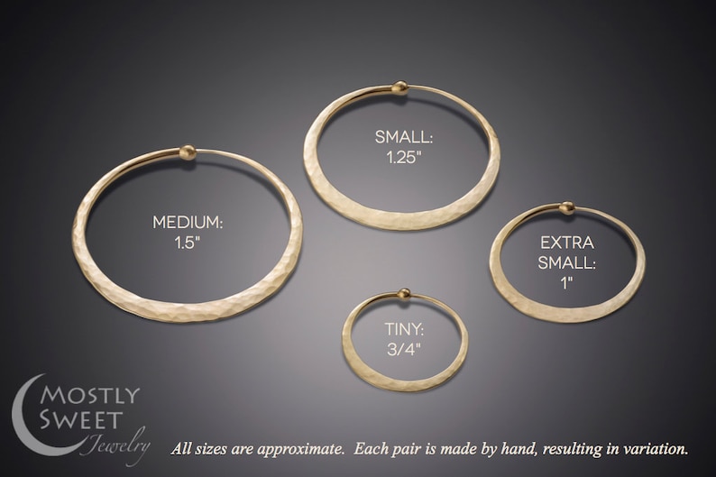 Size comparison of hammered solid 14k gold hoop earrings against dark gray background with Mostly Sweet Jewelry logo. Four different sizes clearly labeled: Medium (1.5"), Small (1.25"), Extra Small (1"), and Tiny (3/4"). Each hoop displays the same hammered texture and endless closure design. Text at bottom notes "All sizes are approximate. Each pair is made by hand, resulting in variation." Warm gold tone shows luxury alternative to silver version.