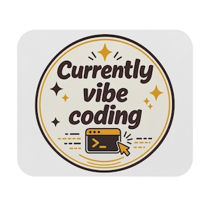 Op de afbeelding: Een rechthoekige muismat met afgeronde hoeken en een cirkelvormig ontwerp. De centrale tekst luidt Currently vibe coding in donkerbruin. Onder de tekst staat een computer-vensterpictogram met een cursor en gele steraccenten.