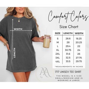 Pode incluir: Uma camiseta unissex cinza escuro com uma tabela de tamanhos. A camisa tem as palavras "Comfort Colors" e "1717 Unisex Tee Shirt" impressas. A tabela de tamanhos mostra as medidas em polegadas.