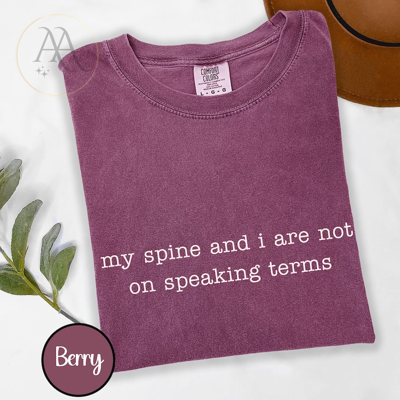 Pode incluir: T-shirt cor de baga com o texto branco "my spine and i are not on speaking terms". A camisa tem gola redonda e mangas curtas. A etiqueta "Comfort Colors" &eacute; vis&iacute;vel.