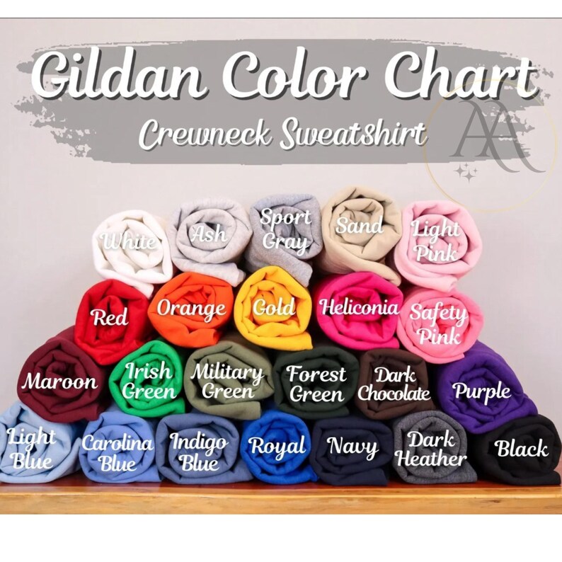 Pode incluir: Uma tabela de cores para camisolas de gola redonda Gildan. A tabela mostra uma variedade de cores, incluindo branco, cinza, cinza desportivo, areia, rosa claro, vermelho, laranja, dourado e mais. Cada cor &eacute; representada por uma camisola enrolada.