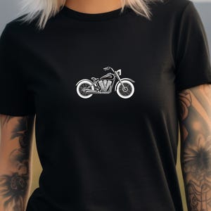 May include: Black t-shirt featuring a white motorcycle graphic. The motorcycle design is a detailed illustration of a classic cruiser-style bike. The shirt is made of a soft, comfortable material, suitable for casual wear.
