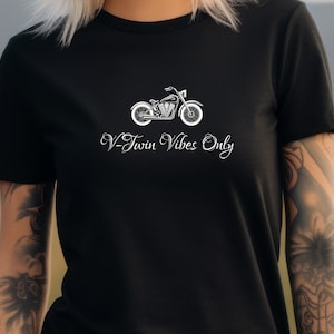 May include: Black t-shirt featuring a white motorcycle graphic and the text "V-Twin Vibes Only". The motorcycle design includes details like the engine, wheels, and handlebars. The text is in a cursive font.