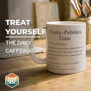 May include: White ceramic mug with the text "Fruity-Pebbles Gate" and a definition. The mug also has the text "TREAT YOURSELF THE DAILY CAFFEINATOR" and a logo. The mug is on a wooden surface.
