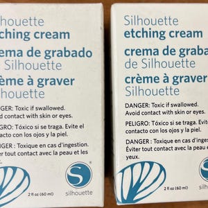 Può includere: Due scatole di crema per incisione Silhouette. Ogni scatola è bianca con testo blu e include avvertenze in inglese, spagnolo e francese. Le scatole contengono 60 ml di crema per incisione.