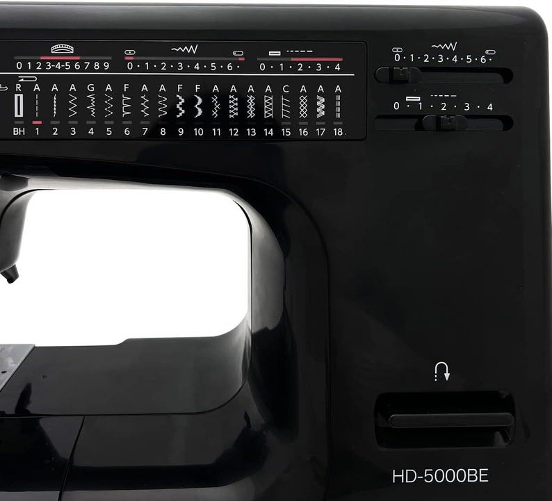 May include: Close-up of a black sewing machine with various stitch selection options and control dials. The machine features a range of stitch patterns and settings, with the model number HD-5000BE visible.