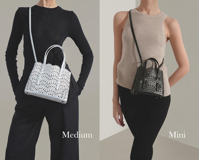 May include: Two handbags, a medium white and a mini black, are displayed. The white bag has a scalloped edge and intricate cut-out design. The black bag has a similar design. Both bags have top handles and adjustable shoulder straps. The word "Medium" and "Mini" are displayed.