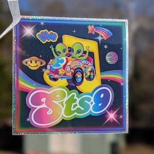 May include: Square sticker with a holographic border featuring a colorful cartoon design. Two green aliens are in a psychedelic car, with the text "sts9" in a rainbow font. Other elements include a rainbow, planets, and the word "love".