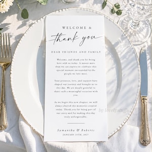 May include: A wedding reception place setting featuring a white plate with gold trim, a folded card with the words "WELCOME & Thank you", and elegant silverware. The card includes a message and the date January 25th, 2027.