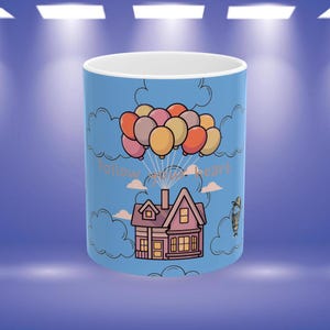 Puede incluir: Taza de cerámica azul con una ilustración de dibujos animados de una casa que flota con globos. La taza tiene el texto "Follow your heart" y está sobre un fondo de cielo y nubes.